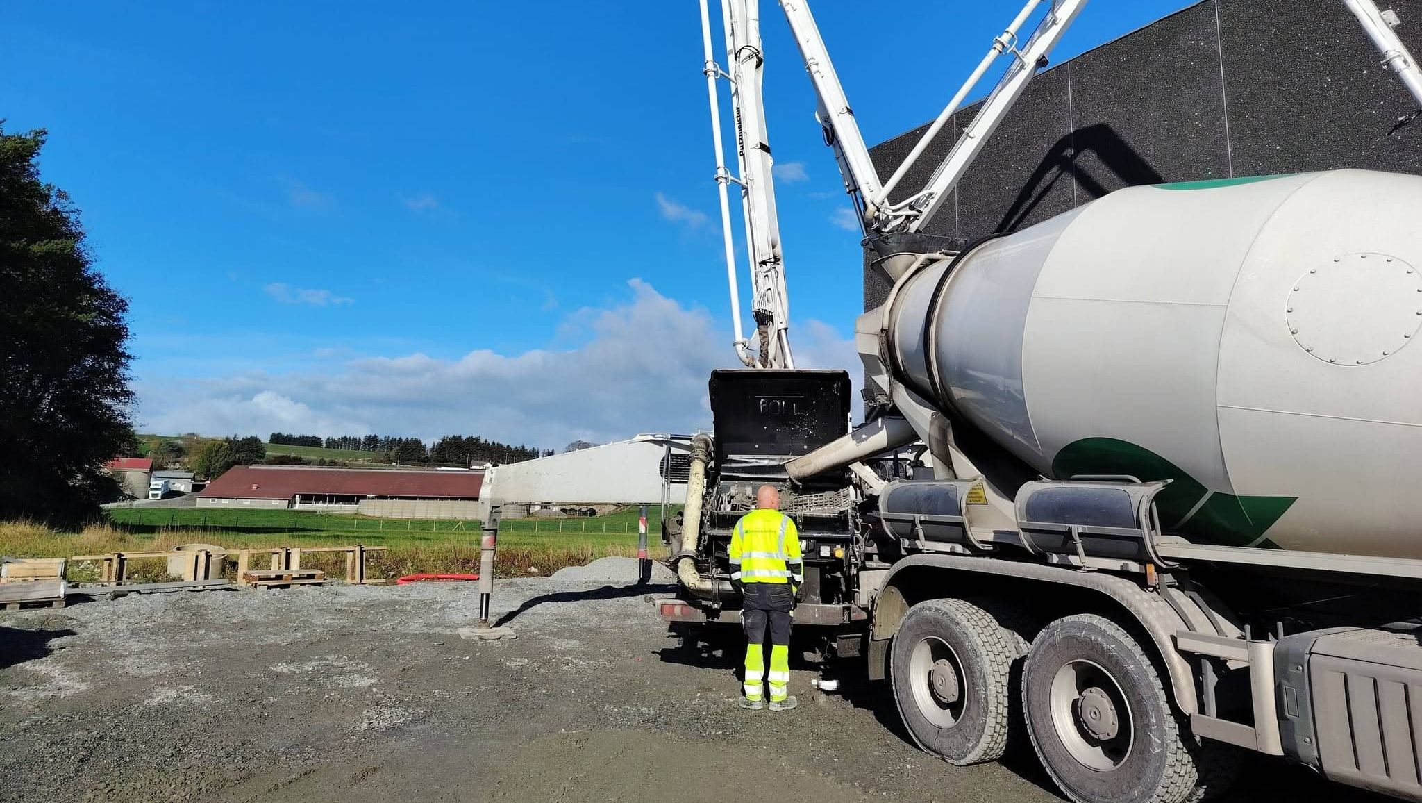 Betongarbeider står ved stor betongpumpe utendørs